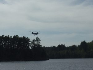 A helicopter hovering over the trees on the edge of Burntside Lake.
