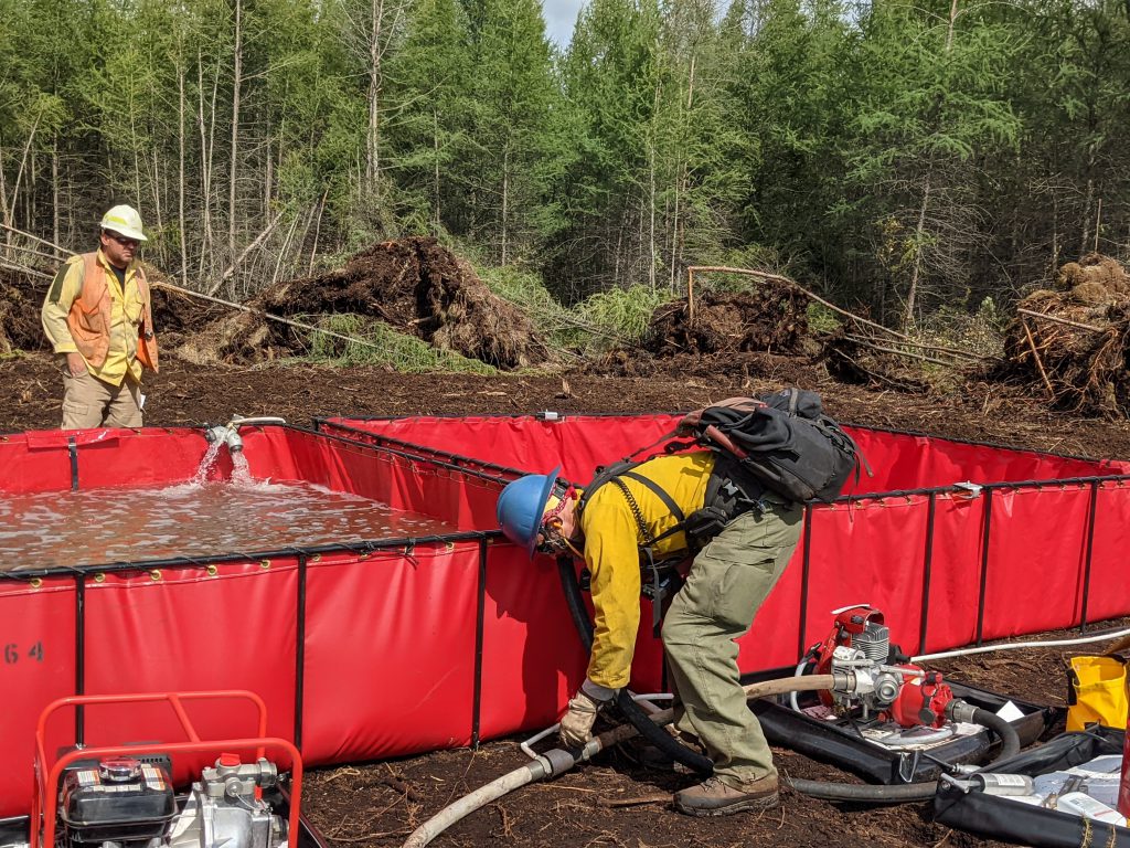 red tank with water and person in yellow shirt next to a pump.