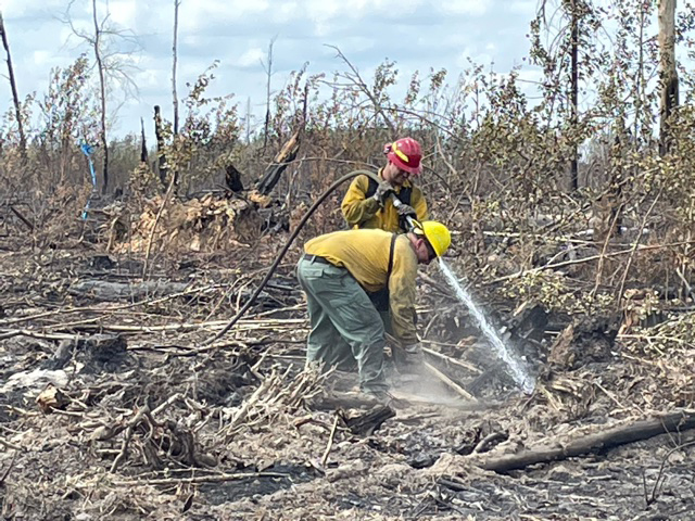 Two people spray water on ground.