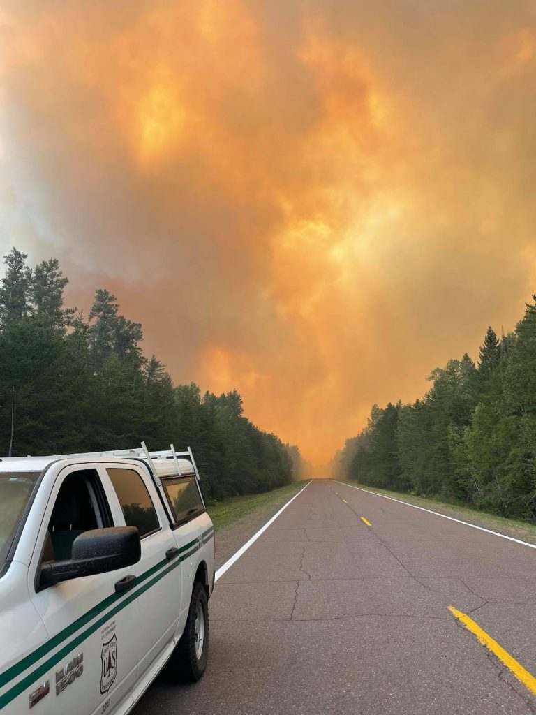 Highway view of orange smoke filled sky and a truck.