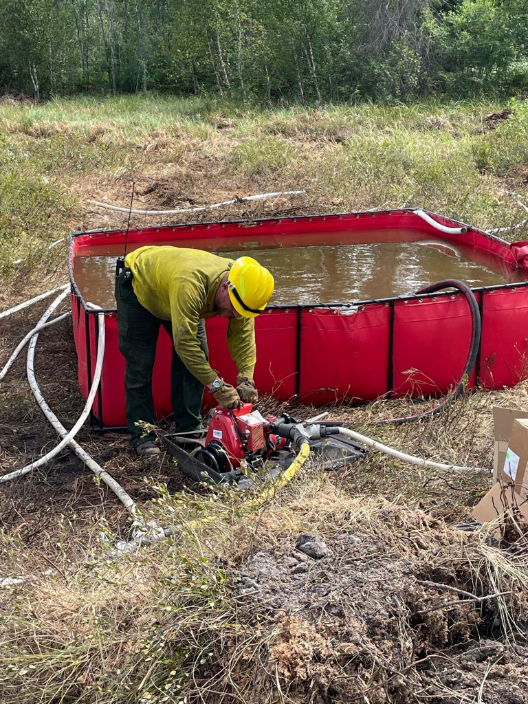 red tank with water and person in yellow shirt next to a pump.