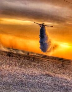 A Fire Boss aircraft drops water at sunset.