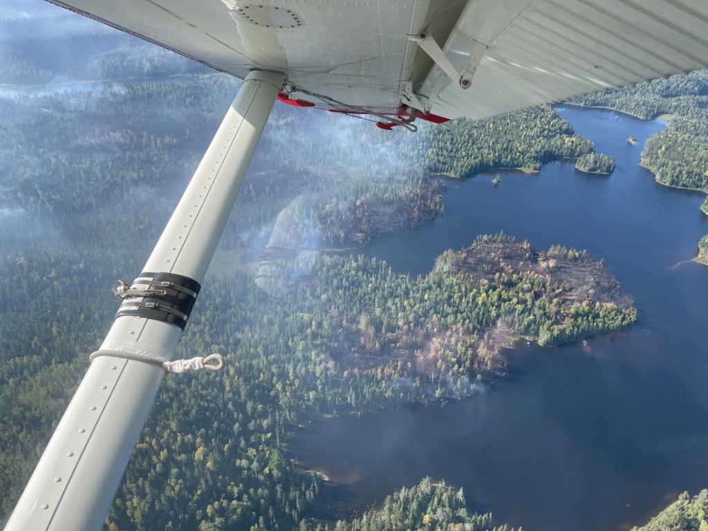 Aircraft wing above water and forest.