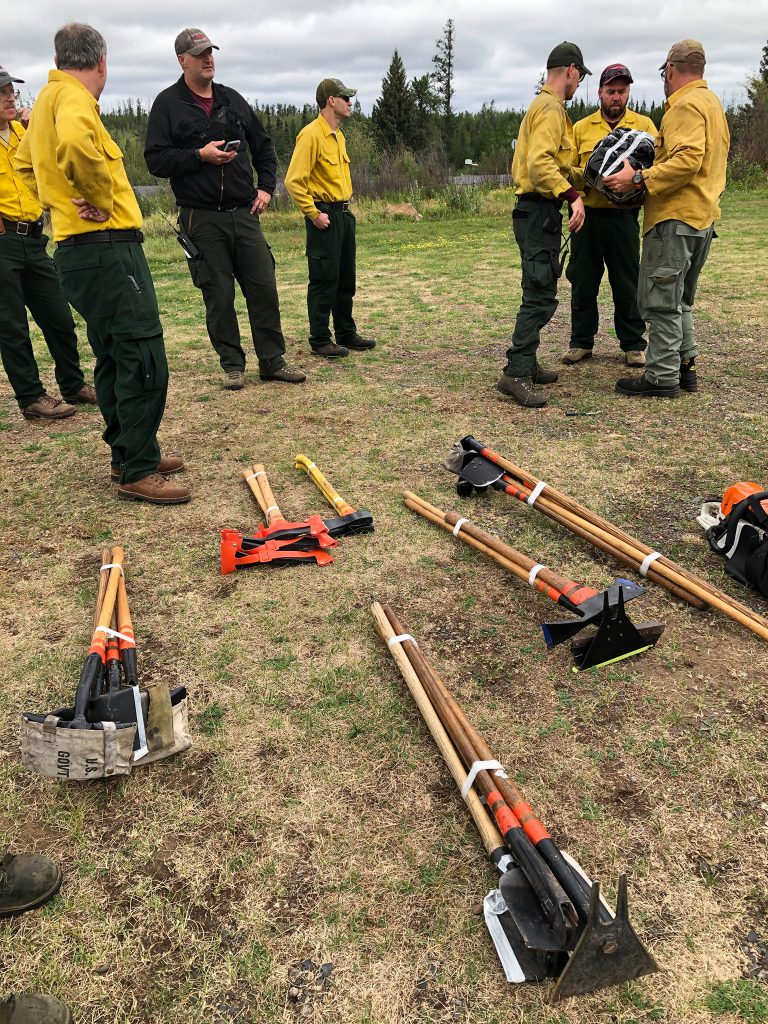 People in yellow shirts stand next to tools on the ground.