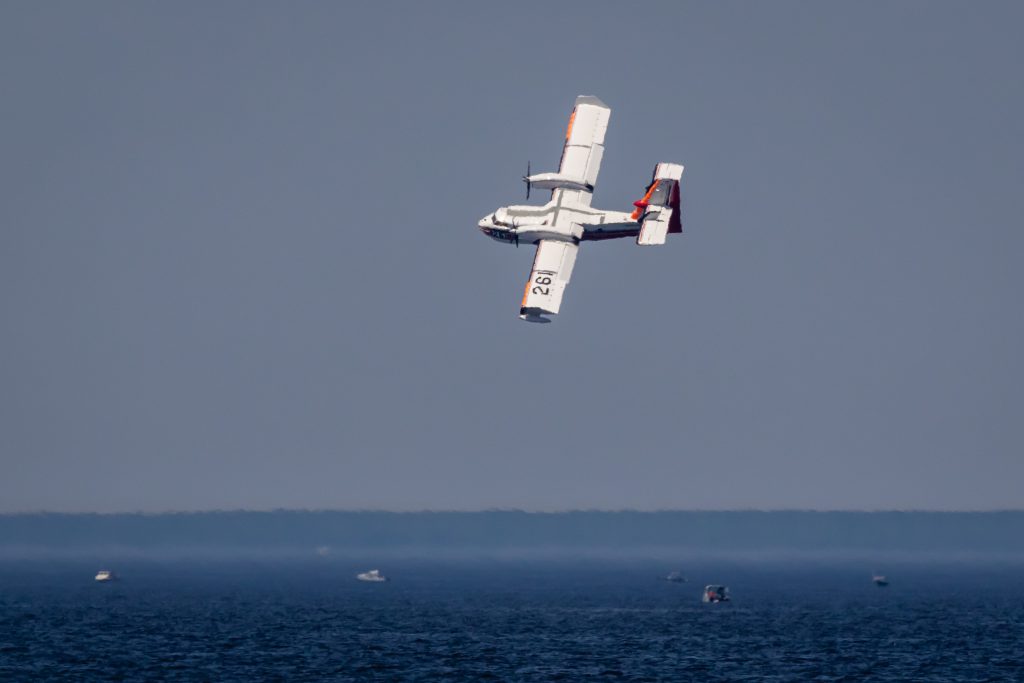 Aircraft prepares to dip from blue water below.