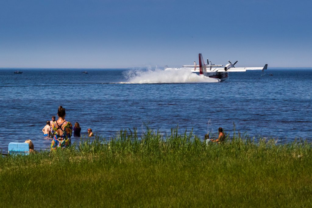 People watch aircraft dip water from lake