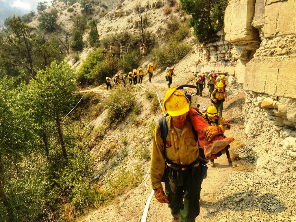 People in yellow shirts climb a rocky hillside.