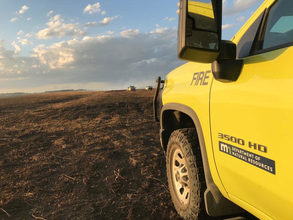 Yellow truck in a bare open soil field.
