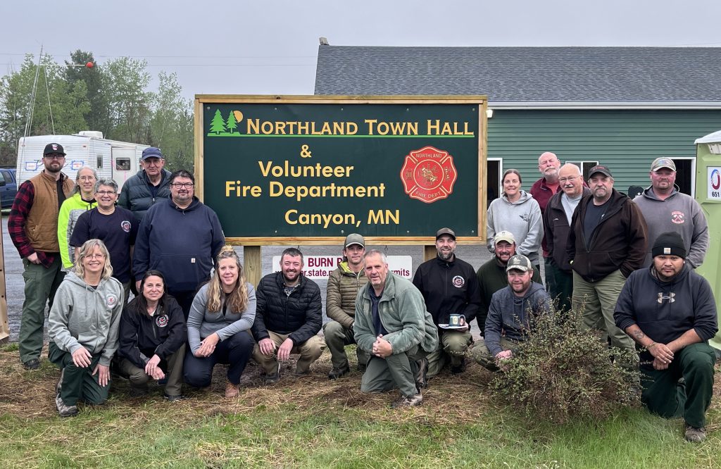 Image of a group photo in an outdoor setting next to a large sign.